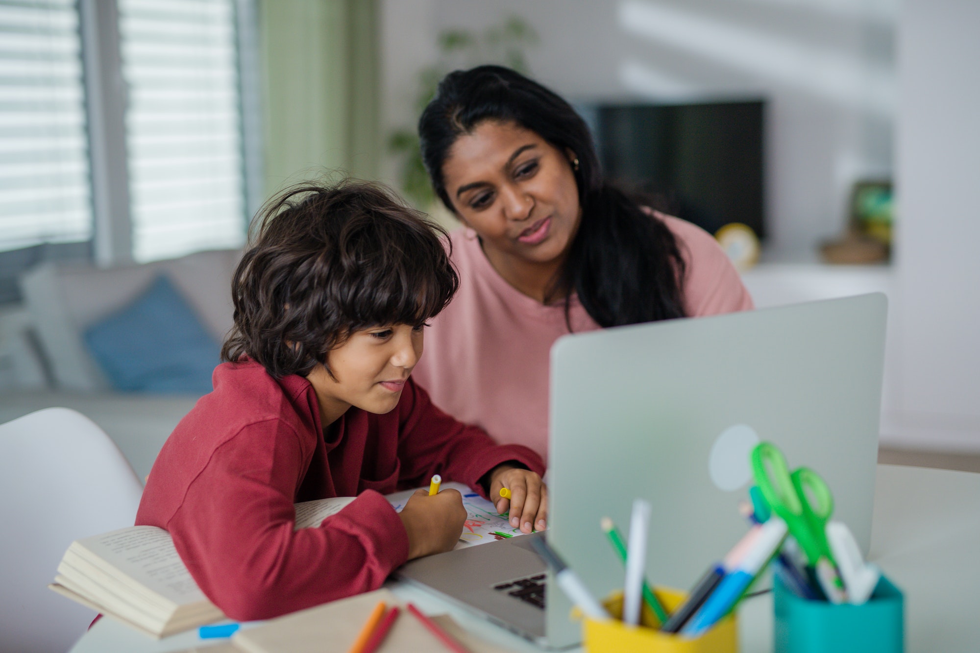 Indian mother with little son using laptop and having online school lesson at home